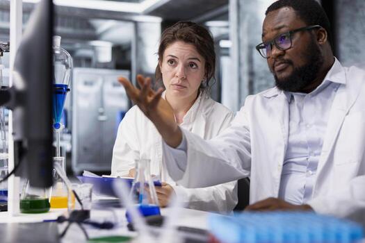 Diagnostic laboratory manager showing intern genetic markers associated with disease risk on PC. Team leader and trainee study DNA strand mapping with genomics analysis program on computer photo
