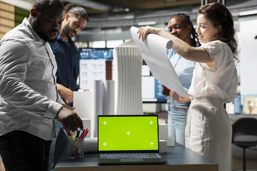 Property developers team reviewing blueprints next to copy space display, collaborating on new urban development residential project through city planning and design. Smart city. photo