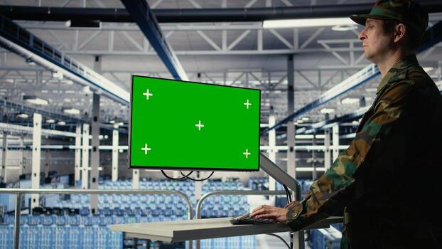 Army programmer in server hub uses AI application on green screen mockup PC to review reconnaissance information. Military data center worker uses AI on chroma key computer to plan mission, camera A photo