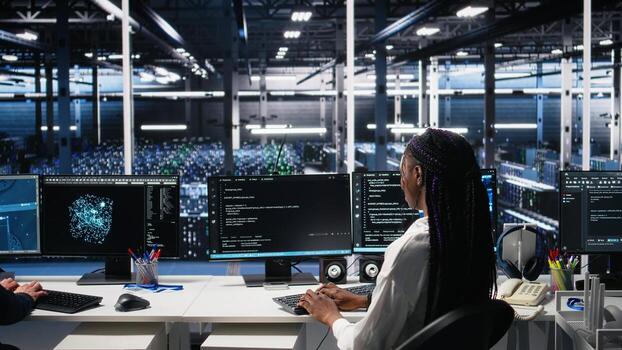 Data center female programmer using machine learning algorithms to analyze datasets. African american woman in server farm using AI neural networks to recognize data patterns, camera A photo