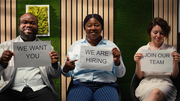 Diverse HR associates showing hiring announcement on printed paper, motivating potential candidates to submit applications and explore open roles in the organization. Vacancy. Camera A. photo