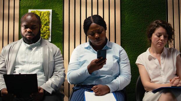 Relaxed female applicant browses phone in hallway lineup and waiting, repeating her speech to present her qualifications and experience on the CV. Preparing for the selection process. Camera A. photo