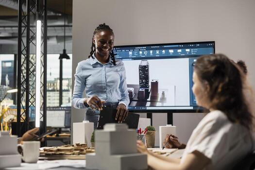 Multiethnic architecture developers team using 3D models in a brainstorming meeting, shows architectural software to work on structural city planning. Residential project for urban development. photo