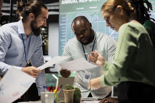 Diverse coworkers team participating in a late night briefing session, exchanging documents and reviewing finance updates. Aligning objectives through collaborative problem solving. photo