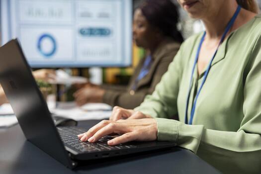 Close up of female administrator typing data in boardroom and solving tasks, immersed in report writing during a briefing session with her team. Using indicators to plan a successful project. photo