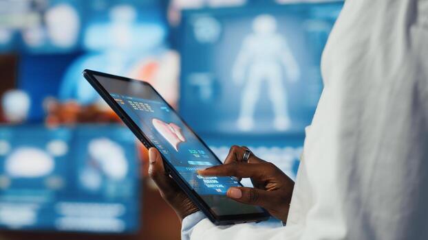 Close up of researcher analyzing human anatomy using tablet app in front of digital health dashboards backdrop. Scientist zooming on touchscreen device display keyboard, analyzing medical scans photo