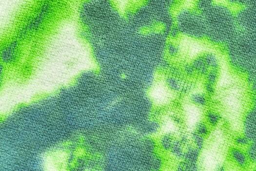 Vibrant green tie-dye fabric texture with abstract organic patterns and soft color transitions. photo