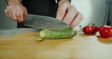Close view Chef man cutting fresh cucumber. slicing cucumber in kitchen with sharp knife. video