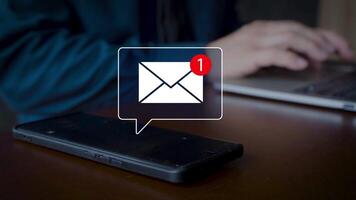 un' smartphone viene visualizzato un e-mail notifica icona con un' rosso mettere in guardia numero uno, simboleggiante comunicazione, tecnologia, e digitale connessione, con un' sfocato persona digitando su un' il computer portatile nel il sfondo. video