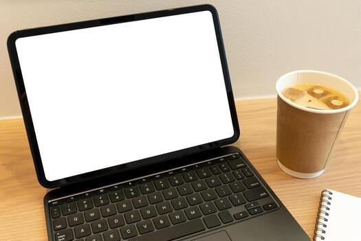 Blank White Screen on Tablet with keyboard and coffee cup at Workspace. a modern and minimalistic office or work from home environment. copy space on the screen and table surface for graphic elements. photo
