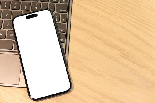 Smartphone with Blank Screen Resting on Laptop Keyboard, Digital Workspace and Connectivity. mobile apps, website designs, mockups, digital content. remote work, technology and design. Copy Space photo