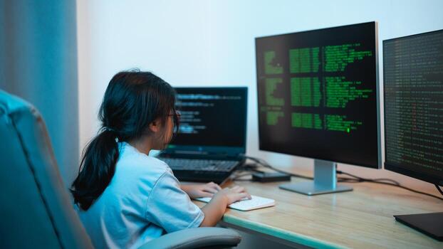 Young Girl Engaged in Programming and Coding Activities at Home with Multiple Computer Monitors Displaying Code in a Modern Workspace photo
