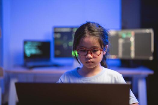 Young Girl Concentrated on Laptop Surrounded by Modern Technology in a Dimly Lit Room with Computer Screens Displaying Code and Data Visualizations photo