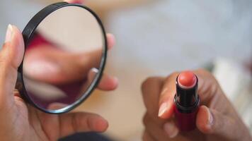 applicering läppstift medan använder sig av en små spegel för precision video