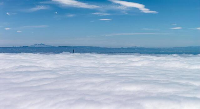 Aerial view of San Francisco covered in clouds, with Salesforce Tower's tip visible and Mount Diablo in the background under a clear blue sky. photo