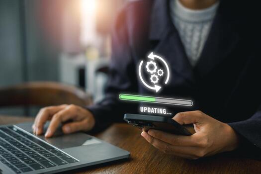 A business professional updates software on a smartphone and laptop, symbolizing technology and progress in a modern office setting. photo