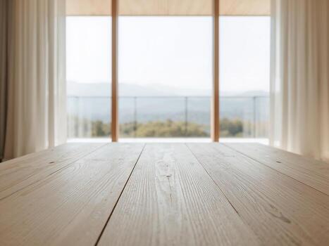 An empty wooden table with a blurred background of a large window looking out at a mountain view. photo