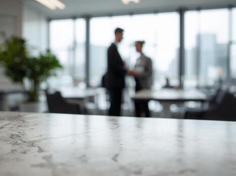 An empty marble table with a blurred background of two business people shaking hands in an office. photo