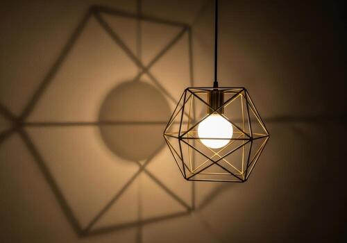 Geometric pendant light casting a large shadow on a textured wall photo