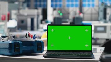 tömma teknik skrivbord i en sol- kraft tillverkning växt med grön skärm, industriell arbetsyta omgiven förbi robot vapen och sol- panel hopsättning rader. övervakning prestanda. video