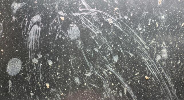 Abstract close up of water droplets and streaks on a dark textured surface creating a dynamic and artistic impression photo