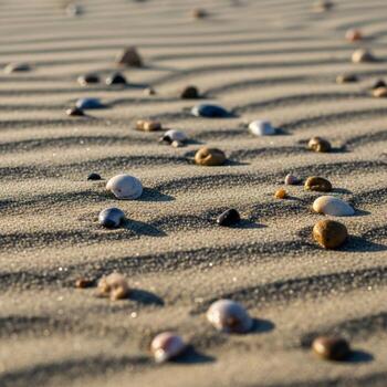 Smooth colorful pebbles scattered across rippled sand dunes on a sunny beach creating a natural textured pattern photo