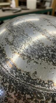 Close up of a textured metallic surface with a mottled speckled pattern reflecting light and shadows photo