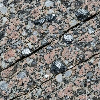 Close up view of a cracked textured granite surface displaying a complex pattern of mineral grains and subtle color variations photo