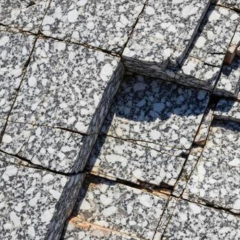 Close up abstract view of weathered cracked asphalt pavement with visible aggregate and shadows creating a textured urban surface photo