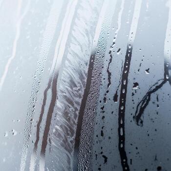 Abstract macro view of water droplets on a window with blurred background textures and streaks creating a moody atmospheric effect photo