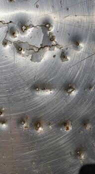 cerca arriba texturizado metálico superficie con numeroso pequeño muescas y sutil lineal grietas foto