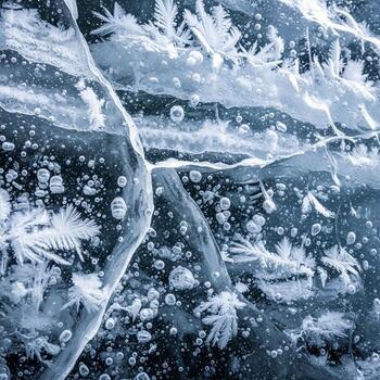 Intricate patterns of frost crystals and trapped air bubbles form a mesmerizing abstract texture on frozen water surface photo