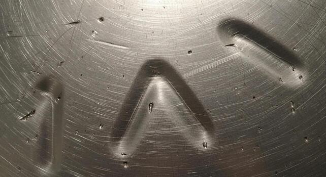 Abstract metallic surface with water droplets and smudges creating interesting shadows and light patterns photo