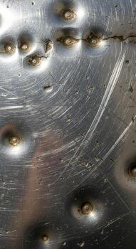 Close up abstract view of a weathered metal surface with visible rivets and scratches showing industrial texture photo