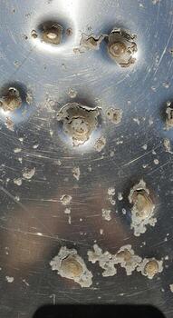 Close up view of a corroded metal surface showing pitting rust and peeling paint with a textured weathered appearance photo