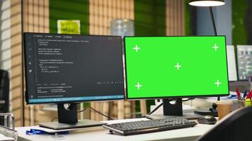 Mockup PC in empty IT startup office displaying programming languages used for building applications. Green screen computer showing code in software development agency with no people in video