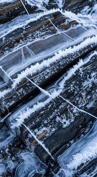 Intricate ice formations create a delicate crystalline pattern over dark textured natural surfaces in a close up abstract view photo