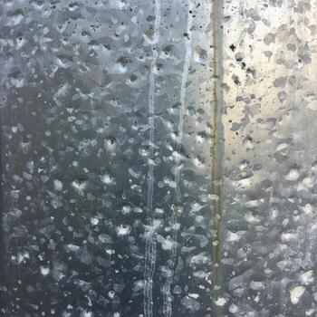 Close up of raindrops on a window pane creating a blurred abstract pattern with diffused light in the background photo