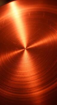 Radiant copper surface with concentric circles reflecting warm golden light in a dynamic abstract pattern photo