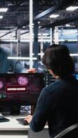 Vertical Technicians in AI server hub panicked by hacking attempt stealing sensitive company data. Team of data center IT experts fighting computer virus triggered by security systems, camera A video