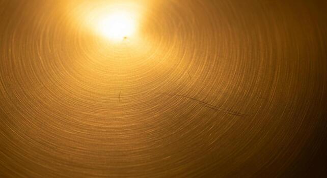 dorado ligero bengalas a través de un texturizado superficie creando un calentar y resumen visual efecto con circular patrones foto