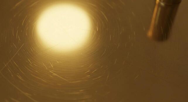 Close up view of a bright warm light source illuminating a textured dusty surface with subtle scratches and a hint of a metallic object photo