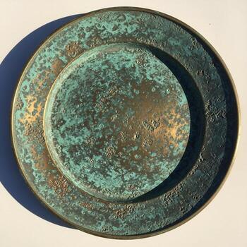 antiguo resistido bronce plato con intrincado circular patrones y verdete pátina fundición un dramático sombra en un neutral superficie foto