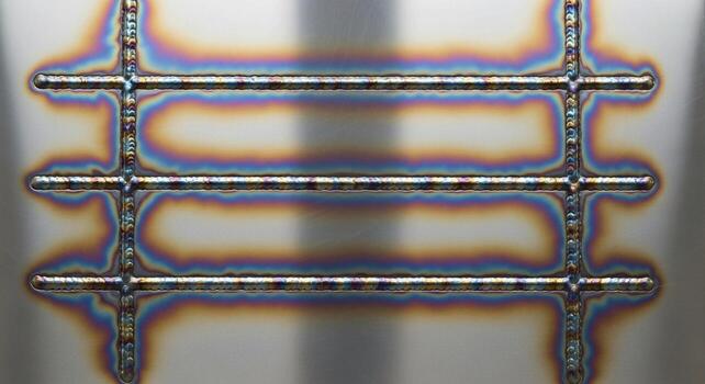 Close up view of a metallic grid structure with heat discoloration showing a rainbow of colors on its surface photo