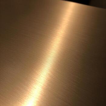 Warm golden light reflects across a textured metallic surface creating a subtle gradient of warm tones and highlights photo