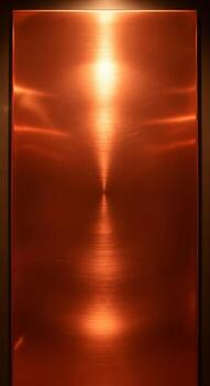Radiant copper surface with a central bright light source reflecting a warm metallic glow and subtle horizontal lines photo