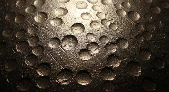 Close up abstract view of a golf ball s dimples with a textured surface and dramatic lighting creating shadows photo
