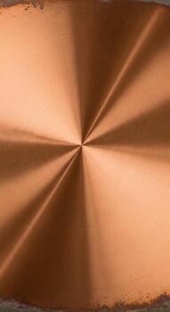 Close up of a brushed copper metal surface with a radial brushed pattern emanating from the center creating a warm metallic texture photo
