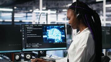 data Centrum dator forskare använder sig av ai assistent till förse användare teknisk Stöd. afrikansk amerikan kvinna i server bruka hantera leva Stöd samtal assisterad förbi artificiell intelligens, kamera en video