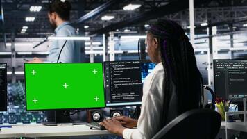 Female technician and coworker in data center review AI diagnostics on isolated screen PC. IT expert and colleague optimize artificial intelligence systems using chroma key computer, camera A video
